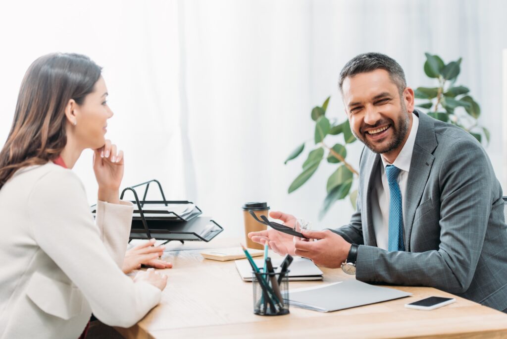 advisor sitting at table smiling and holding glasses with investor in office